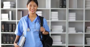 A medical student carries a backpack and holds textbooks. She's also wearing scrubs and a stethoscope around her neck.