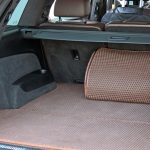 The inside of an open trunk of a luxury SUV with brown textured mats and a matching storage organizer.