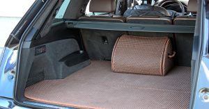 The inside of an open trunk of a luxury SUV with brown textured mats and a matching storage organizer.
