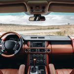 The interior of a new car, looking out on an empty road. The car is modern with brown and black upholstery.