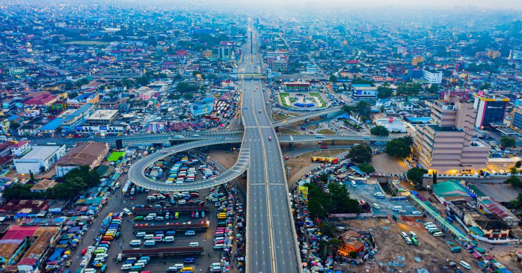 An aerial view of a crowded city with new urban landscaping and a winding road in the middle of the city.