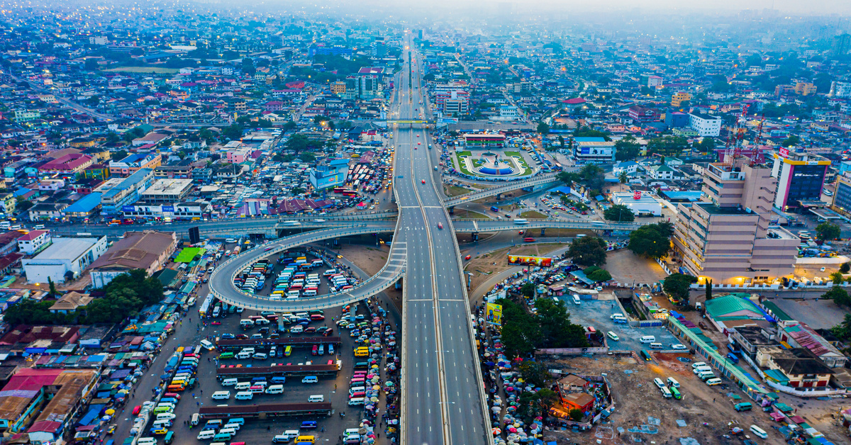 An aerial view of a crowded city with new urban landscaping and a winding road in the middle of the city.